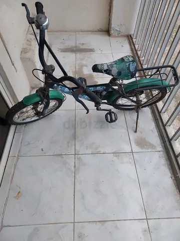 Green childrens bike with rear rack — needs repair