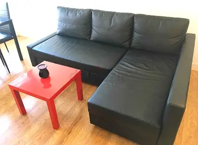 Black L-shaped leather sofa with  storage chaise - good condition