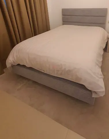 Grey upholstered double bed with padded headboard - used, good condition