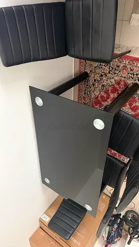 4-seater glass-top dining table with black faux leather chairs from PAN emirates
