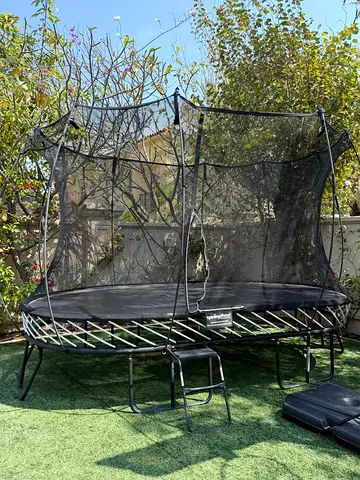 Spring Free brand oval trampoline with safety enclosure and ladder.