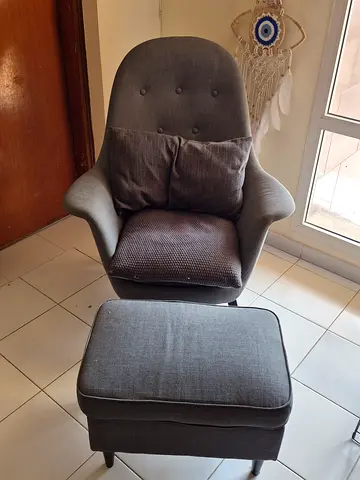 Grey upholstered accent armchair with matching ottoman.