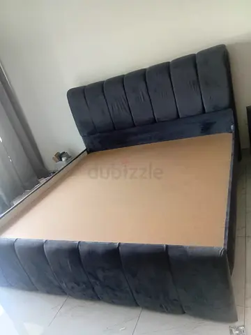 Grey upholstered bed frame with padded headboard