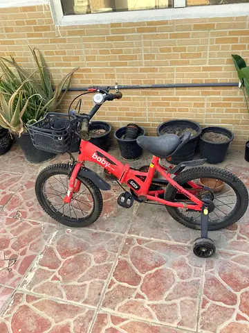 My childs red bike with training wheels and basket