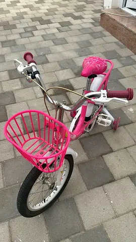 Pink kids bicycle with training wheels and front basket bike
