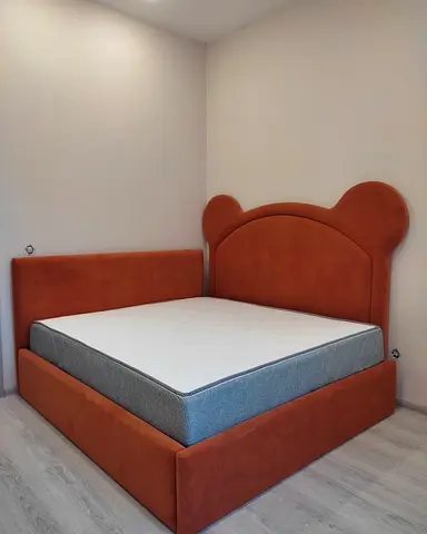 Orange velvet upholstered bed with rounded bear ear headboard