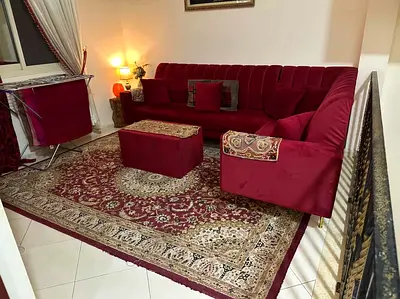 Maroon L-shaped velvet sectional sofa with ottoman and matching rug