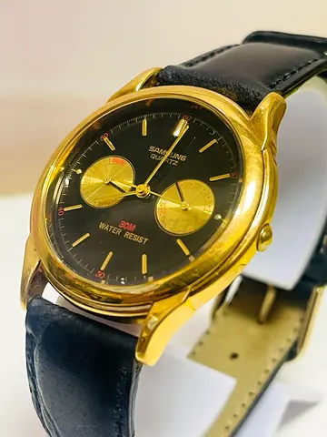 Samsung quartz wristwatch with a gold-tone case, black dial, and a leather strap