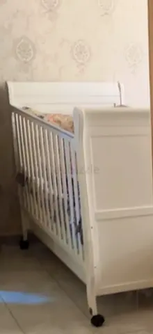 My white wooden baby crib on wheels, good condition