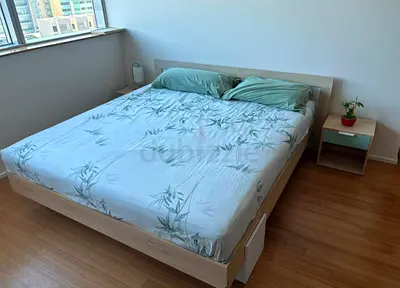 Queen-sized wooden bed frame with mattress and bedside table