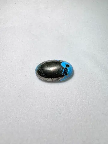 Small polished cabochon — looks like turquoise with black matrix