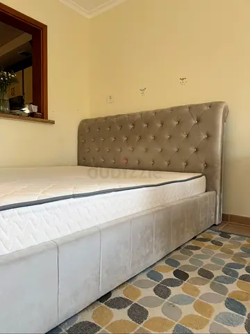 Grey upholstered bed with tufted headboard and storage base
