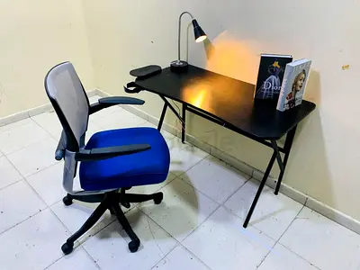 My black computer desk with blue ergonomic swivel chair