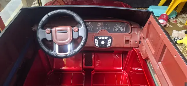 My red battery-powered kids ride-on car with steering wheel.