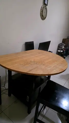 Wooden oval dining table with black base and 4 chairs and a black box under the table