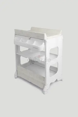White baby changing table with cushioned pad, storage shelves, built in bath and wheels