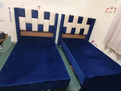 Two navy velvet single beds with matching padded headboards