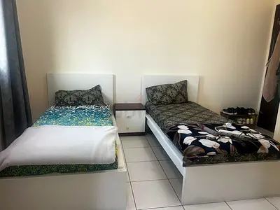 Two single white bed frames with mattresses and nightstand