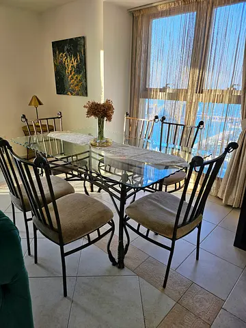 Glass-top metal dining table with 6 cushioned chairs