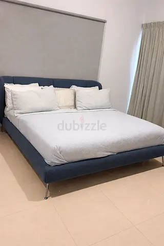 Blue upholstered bed with mattress and metal legs