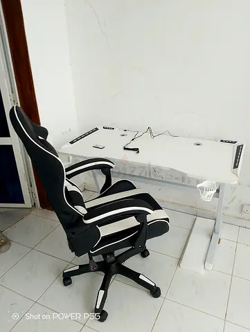 White height-adjustable computer desk with black  white gaming chair