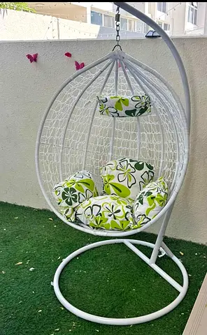 My white hanging egg chair with green floral cushions