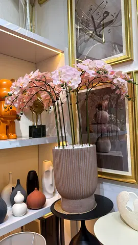 Artificial orchid arrangement in ribbed ceramic pot with decorative vases