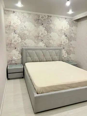 Light grey upholstered bed frame with mattress and 2 bedside tables