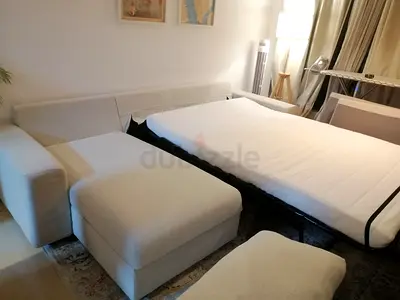 Beige L-shaped sofa with pull-out bed — good condition