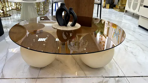 Round glass coffee table with sculptural cream bases