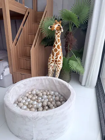Neutral marble ball pit with soft balls and large plush giraffe
