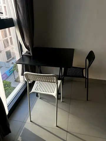 Compact black dining table with two modern plastic chairs