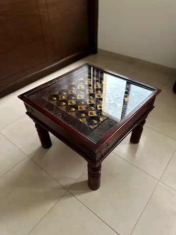 Carved square wooden coffee table with glass top and metal inlay