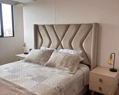 Queen upholstered bed with winged headboard and two bedside tables - good condition