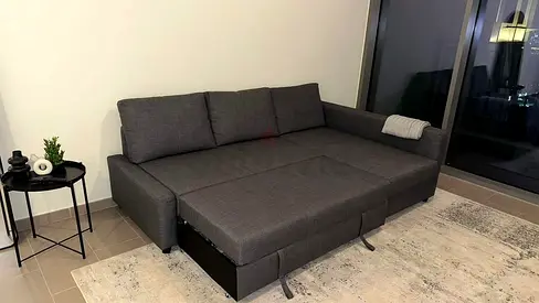 Dark grey L-shaped sofa bed in good condition