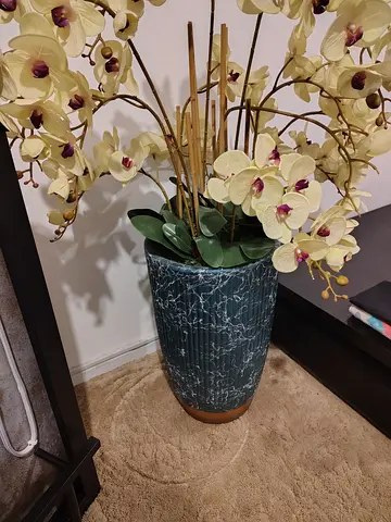 Tall artificial orchid arrangement in decorative blue ceramic vase used