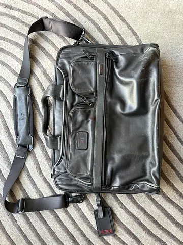Tumi Black leather shoulder laptop bag with inner and outer pockets – average condition
