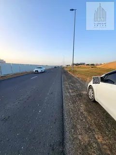 Commercial land for sale in Al Helio 2, Ajman, on a main street. Ground floor and mezzanine permit.