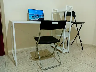 Simple white study desk with folding chairs and shelf