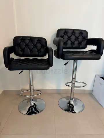Pair of adjustable black faux leather bar stools with armrests