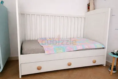 White wooden baby cot with storage drawers + mattress and linen