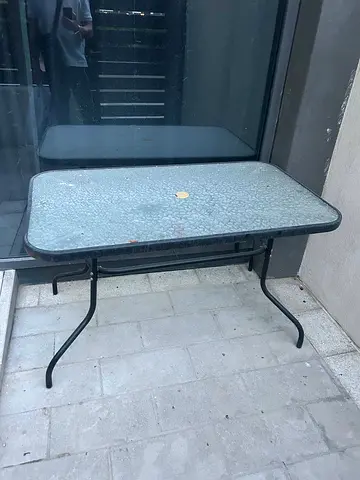 Used outdoor glass-top folding patio table — sturdy metal frame