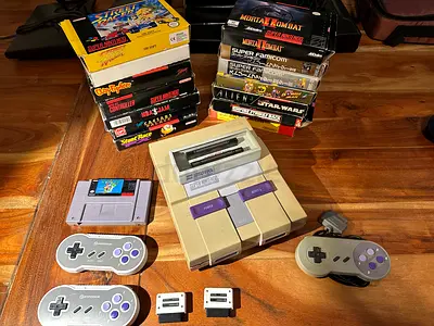 Super Nintendo (SNES) console with 16 classic cartridges, 3 controllers and original adapters.