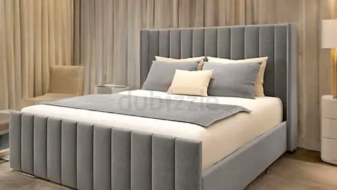 Grey upholstered queen bed with vertical channel headboard and storage base