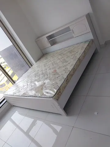 White wooden single bed with attached headboard/storage and mattress
