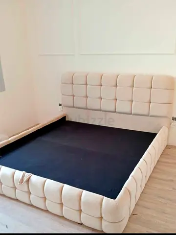 Beige upholstered queen bed frame with padded headboard