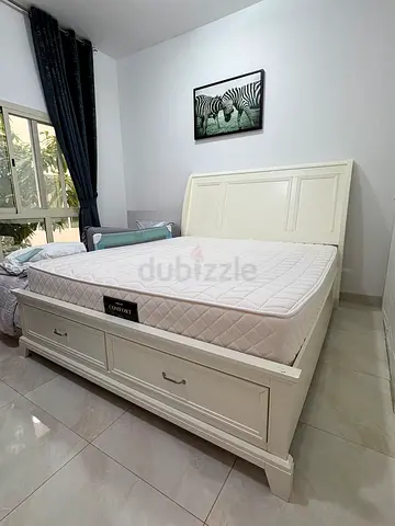 White wooden king bed frame with storage drawers and mattress