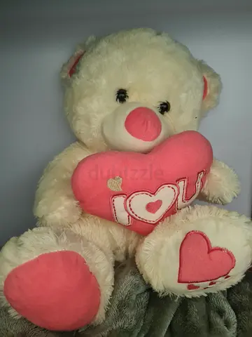 Large cream teddy bear holding pink heart plush