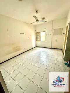 A spacious studio apartment with an open view, window air conditioning, and a separate kitchen with