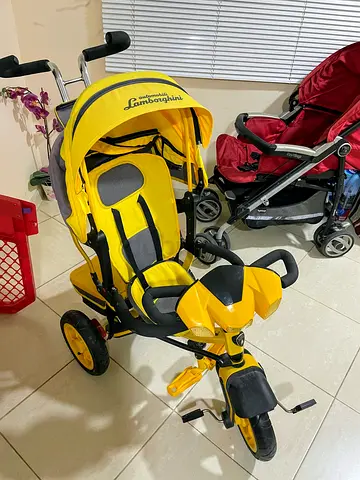 Yellow children tricycle with push handle